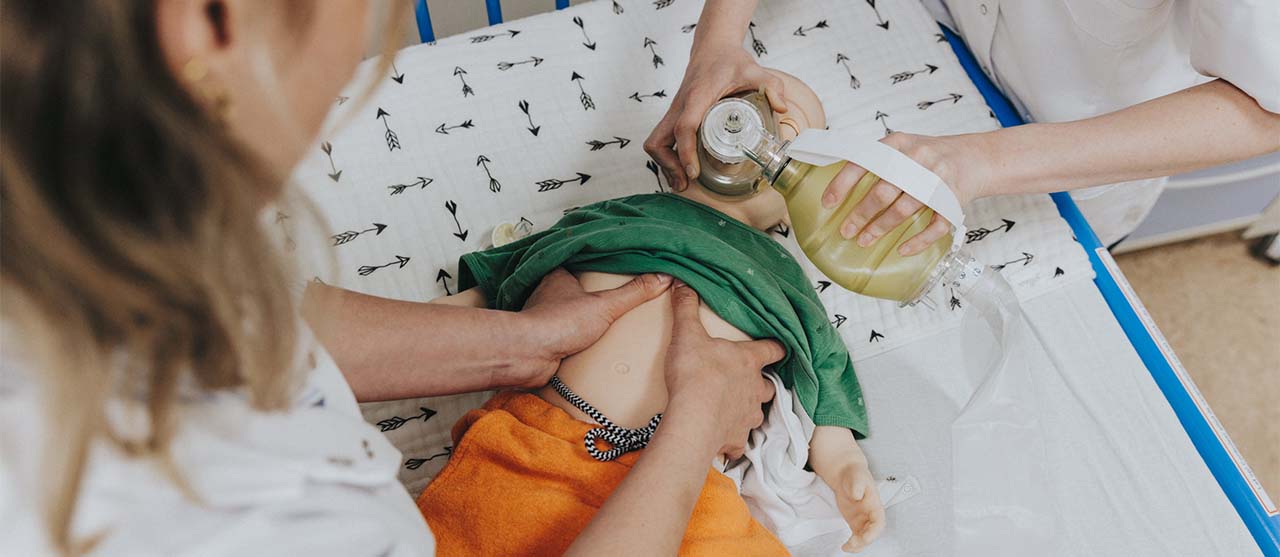 Een studente verpleegkunde aan HOGENT oefent reanimatietechnieken op een realistische babypop.