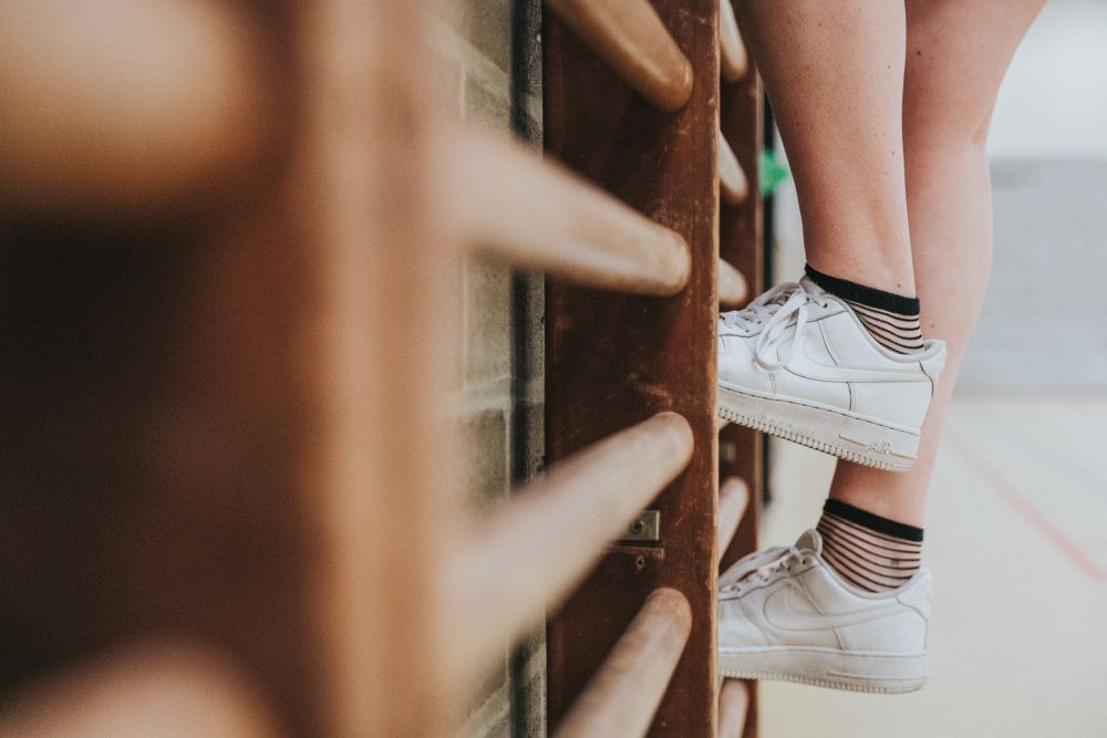 Een studente uit de educatieve bachelor LO en bewegingsrecreatie klimt op een klimrek in de sporthal.