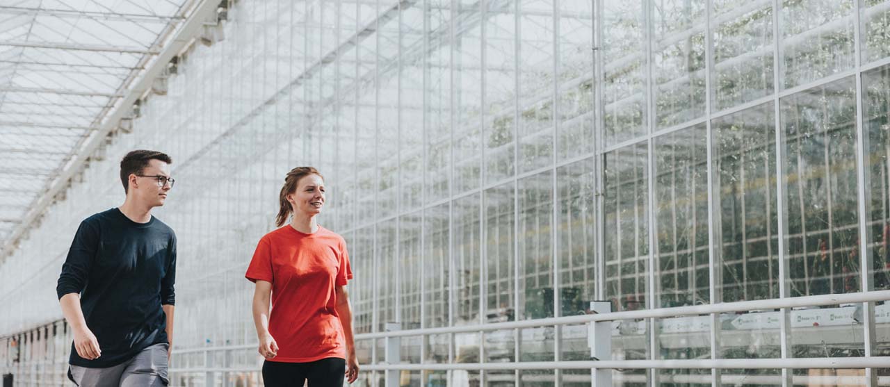 Twee landbouwstudenten van HOGENT lopen langs een grote glazen serre.