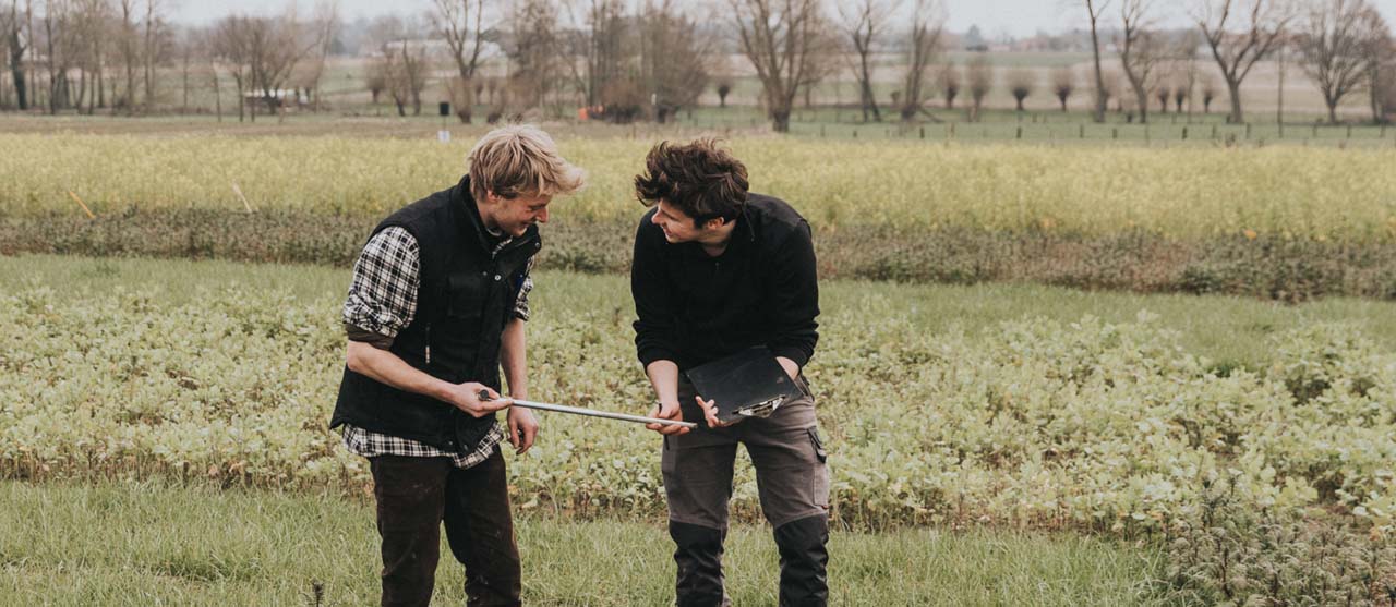 Twee studenten landbouw lachend op een proefveld in Bottelare.