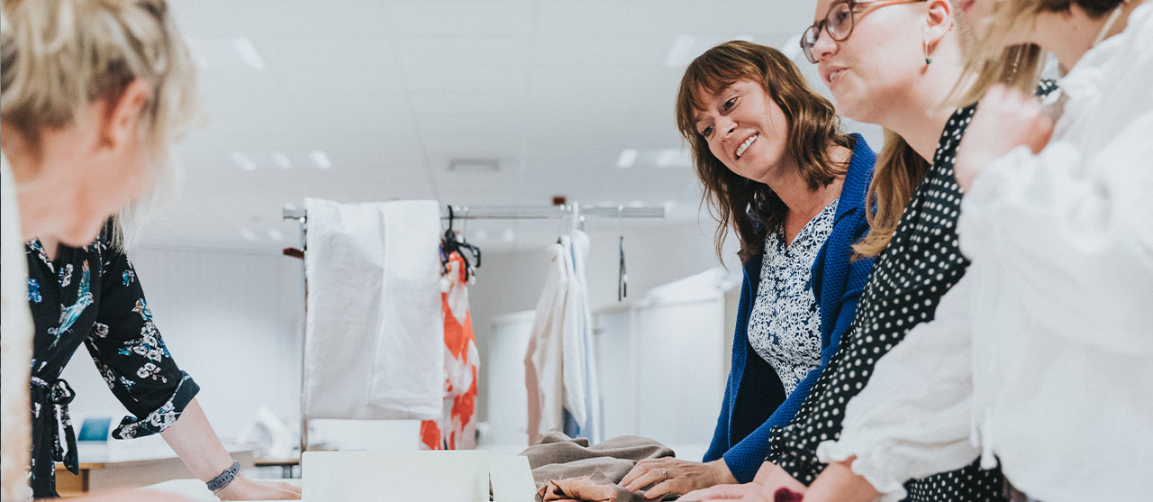 Studenten modetechnologie van HOGENT bespreken patronen aan een patroontafel.