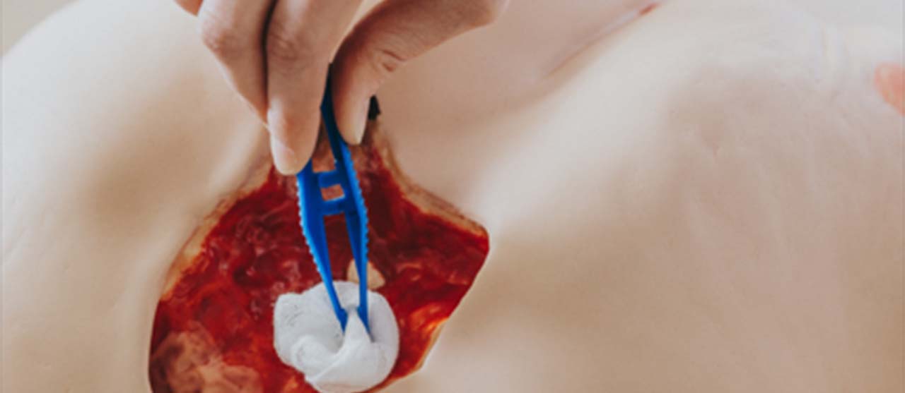 Een studente uit het graduaat basisverpleegkunde van HOGENT oefent wondzorg op een pop.