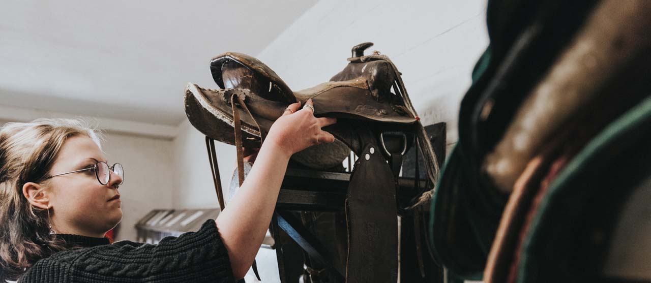 Een studente dierenzorg van HOGENT kiest het juiste zadel uit voor een paard.
