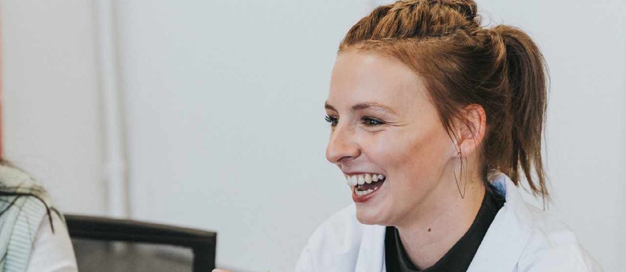 Lachende studente Health Care Management tijdens projectwerk bij een partnerorganisatie van HOGENT.