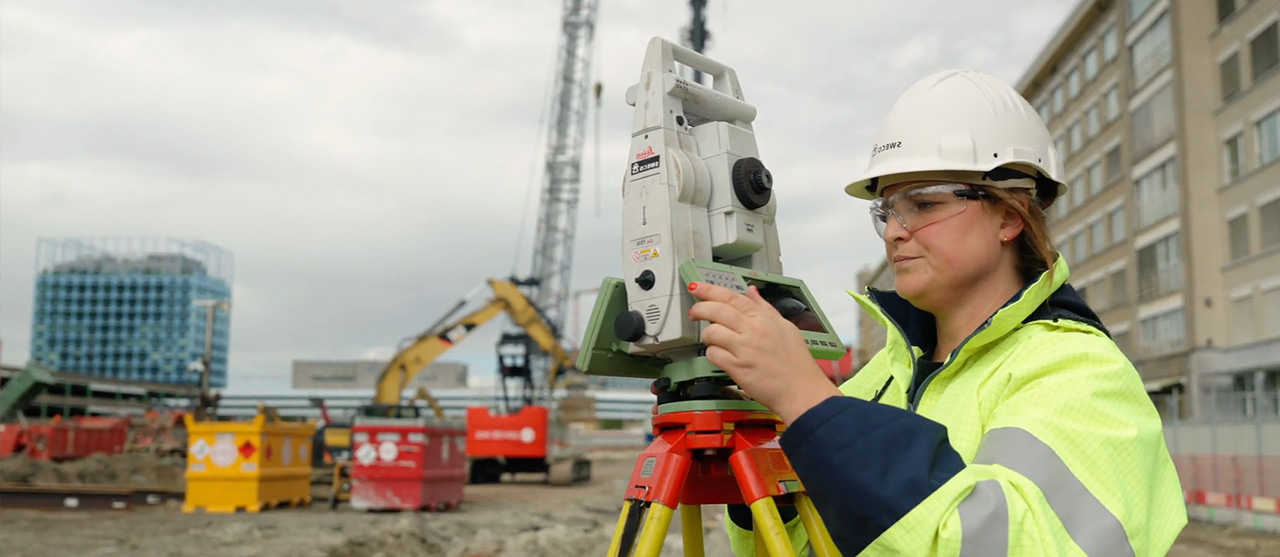 Een studente landmeten van HOGENT aan het werk met een meettoestel op een werf.