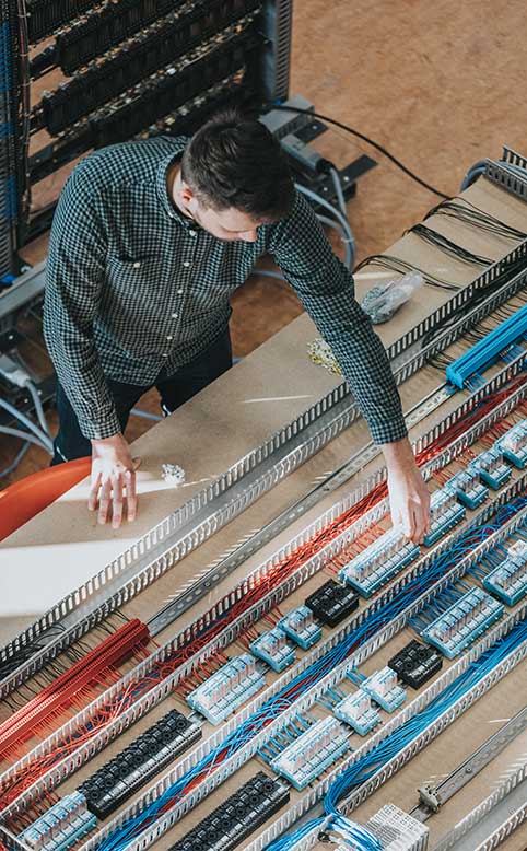 Een student uit de graduaatsopleiding elektromechanische systemen met afstudeerrichting meet- en regeltechnieken aan HOGENT werkt aan een industriële machine om die te automatiseren.