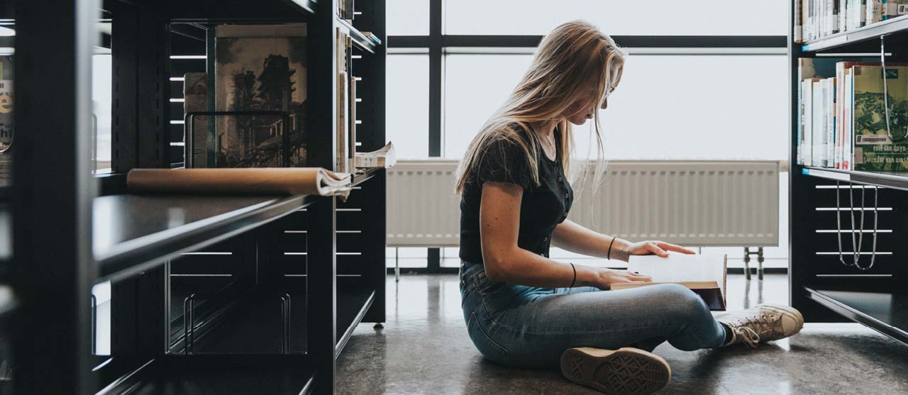 Studente secundair onderwijs op zoek naar vakliteratuur in de bibliotheek van campus Ledeganck.