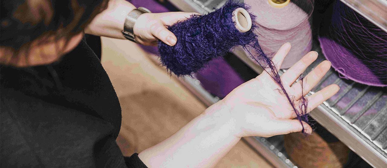 Studente textieltechnologie van HOGENT voelt aan paars getextureerd garen.